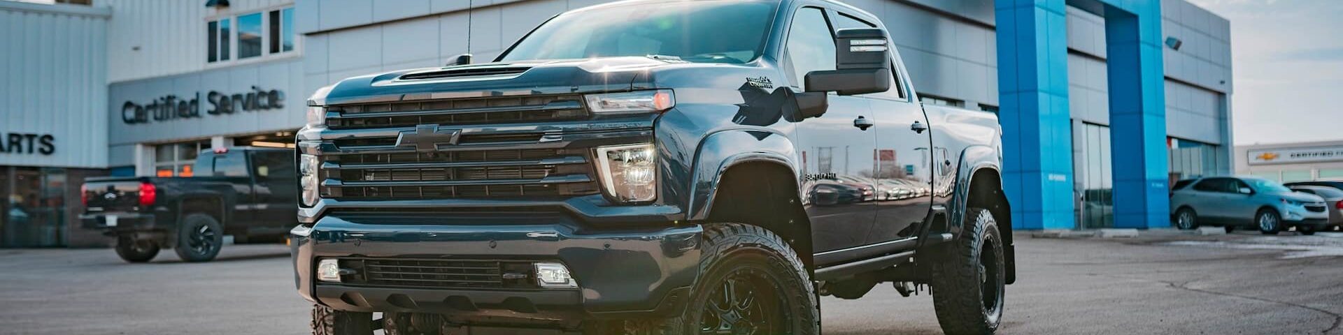 Black Chevrolet Silverado truck parked at a dealership, showcasing its rugged design and modern features.