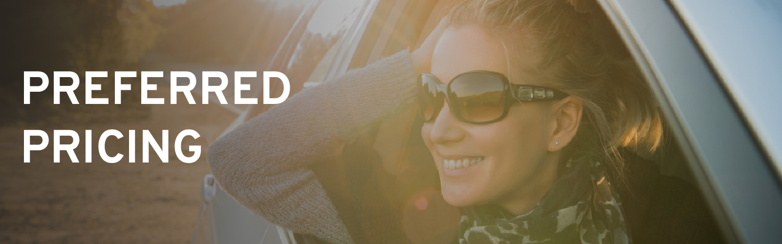 Woman smiling from car window, wearing sunglasses. Text says "Preferred Pricing." Bright, sunny day.