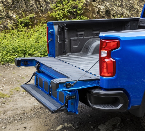 Open blue pickup truck tailgate in a rugged outdoor setting, showcasing the bed and tailgate design.