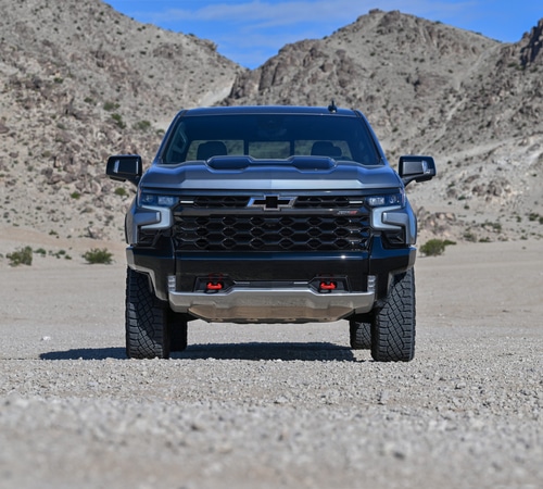 Black pickup truck in a rocky desert landscape under a clear blue sky.