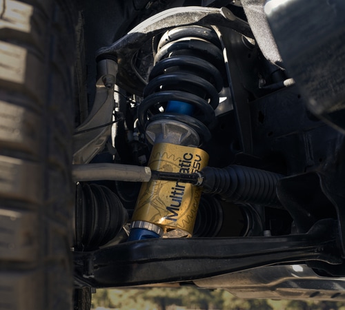 Close-up of a Multimatic DSSV suspension system on a vehicle with a visible tire.