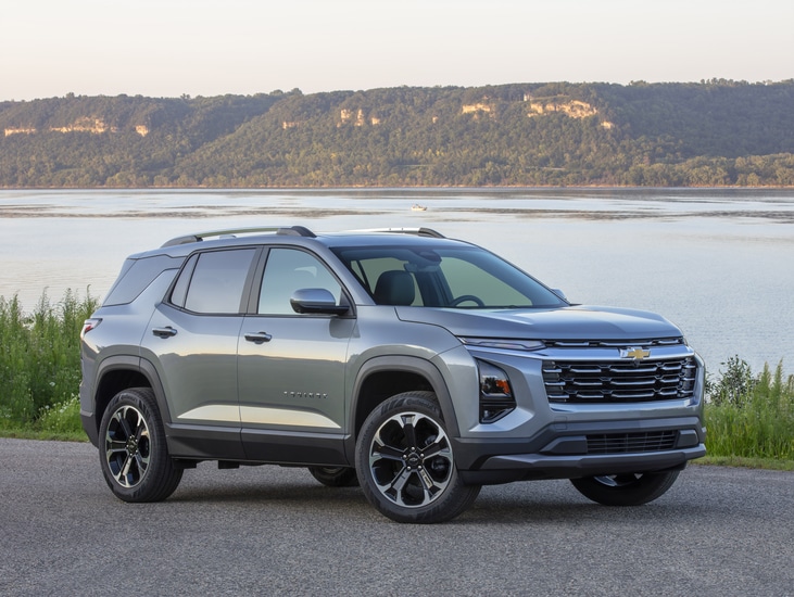 Red SUV with a sleek design parked indoors. The vehicle has prominent headlights and a bold front grille. The setting features a modern and spacious environment with architectural elements in the background.