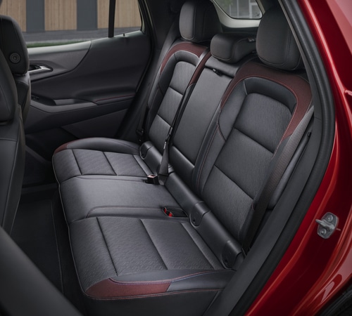 Back seats of a red car with black and red accents, highlighting spacious legroom and modern design.