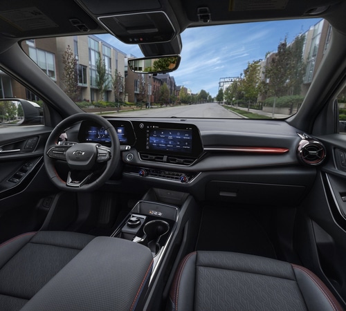 Modern car interior with digital dashboard, steering wheel, and urban street view through windshield.