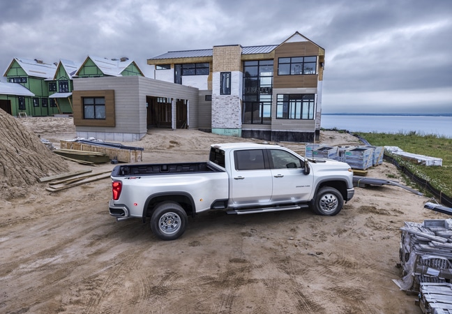 White pickup truck parked at a construction site with partially built houses in the background.