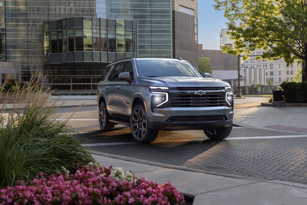 Silver SUV parked in an urban setting with modern glass buildings and greenery in the background.